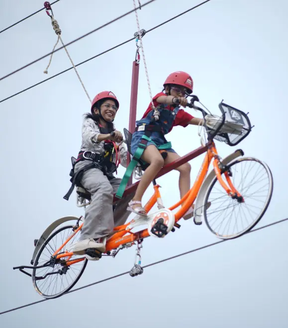 Couple riding sky cycle suspended in mid-air