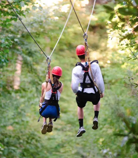Couple enjoying tandem zipline ride over scenic landscape